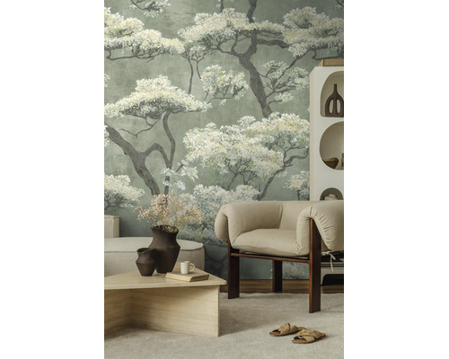 Fotobehang met grote bloesembomen in een lichte woonkamer met beige fauteuil en houten tafel.