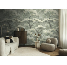 Woonkamer met vliesbehang met boompatroon, lichte bank, donker dressoir en ronde fauteuil.