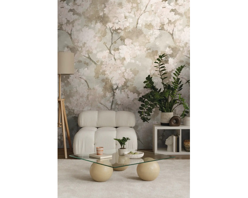 Moderne woonkamer met bloemenbehang, lichte fauteuil, glazen tafel met ronde poten, vloerlamp en kamerplanten op een licht tapijt.