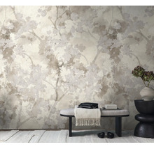 Vliesbehang met floraal patroon van takken en bloesems in een lichte, modern ingerichte kamer met een bankje en een decoratieve vaas.