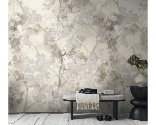 Vliesbehang met floraal patroon van takken en bloesems in een lichte, modern ingerichte kamer met een bankje en een decoratieve vaas.