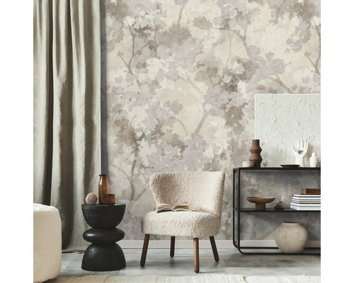 Vliesbehang met bloemrijk takken- en bladerpatroon in neutrale tinten in een modern ingerichte woonkamer met fauteuil en wandplank.