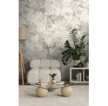 Behang met abstract bladpatroon in een moderne woonkamer met witte fauteuil en glazen tafel.