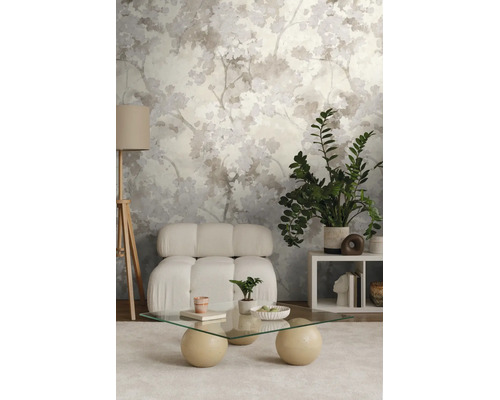 Behang met abstract bladpatroon in een moderne woonkamer met witte fauteuil en glazen tafel.