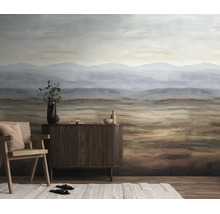 Fotobehang met berglandschap in aardetinten achter een dressoir van donker hout en een fauteuil in de woonkamer.