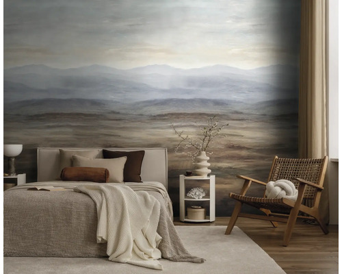 Slaapkamer met fotobehang van een berglandschap in bruin en blauw, ingericht met een bed en een houten stoel.