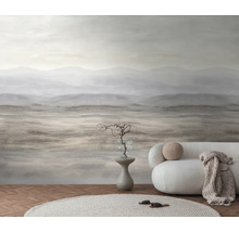 Fotobehang met abstract berglandschap in aardetinten in een minimalistische woonkamer met een witte bank en een licht tapijt.
