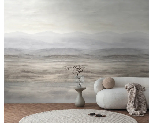 Fotobehang met abstract berglandschap in aardetinten in een minimalistische woonkamer met een witte bank en een licht tapijt.