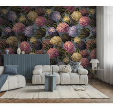 Vliesbehang met hortensia-motief in een moderne woonkamer met witte bank en blauwe bijzettafel.