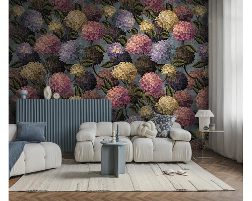 Vliesbehang met hortensia-motief in een moderne woonkamer met witte bank en blauwe bijzettafel.