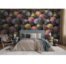 Slaapkamer met fotobehang met groot hortensia-bloemmotief, een tweepersoonsbed en een houten fauteuil op een tapijt.
