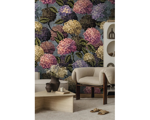Fotobehang met een grootschalig botanisch hortensia-patroon in een moderne woonkamer met een fauteuil en salontafel.