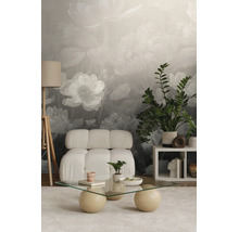 Fotobehang met grote bloemen in grijs en wit in een modern ingerichte woonkamer met een witte fauteuil en een glazen tafel.