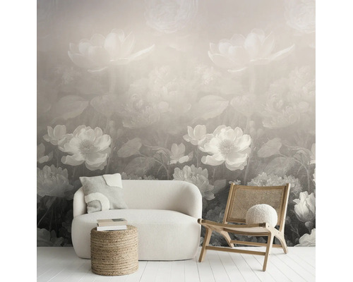 Vliesfotobehang met groot bloemenpatroon in een modern ingerichte woonkamer met witte bank, houten stoel en jute hocker.