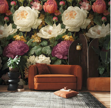 Vlies fotobehang met grote, geschilderde bloemen in een woonkamer met fluwelen bank en planten.