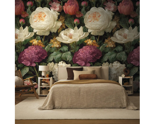 Fotobehang met groot bloemenpatroon van rozen en pioenen in de slaapkamer achter een bed met beige beddengoed.