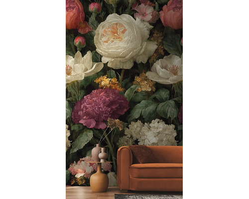 Vliesbehang met grootbloemig, antiek bloemenpatroon, pioenrozen en rozen in crème en donkerrood, achter een bank in de woonkamer.
