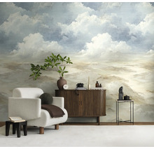 Lichte woonkamer met fotobehang dat een bewolkte lucht in schilderstijl toont. Ervoor staan een witte fauteuil en een dressoir van donker hout.