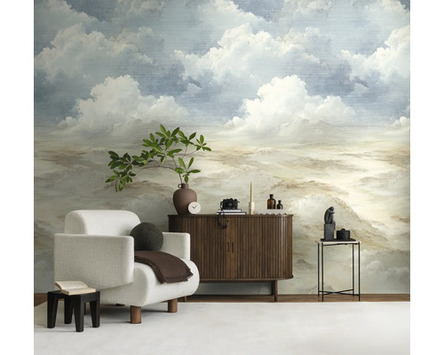 Lichte woonkamer met fotobehang dat een bewolkte lucht in schilderstijl toont. Ervoor staan een witte fauteuil en een dressoir van donker hout.