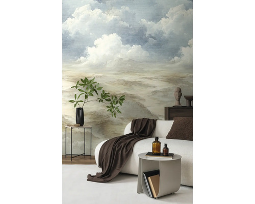 Vliesbehang met geschilderd wolkenlandschap in een moderne woonkamer met witte bank en decoratie.