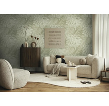 Moderne woonkamer met vliesbehang met monstera-motief, lichtgekleurde bank, donker houten dressoir en organisch gevormd tapijt.