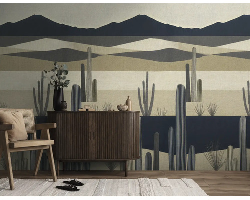 Modern vliesbehang met gestileerd woestijnlandschap, bergen en cactussen in een woonkamer met dressoir en houten stoel.