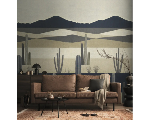 Vliesbehang met een gestileerd woestijnlandschap met bergen en cactussen in een modern ingerichte woonkamer met een bruine bank.