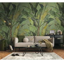 Fotobehang met grote bananenbladeren in vintage-stijl achter een bank in een georganiseerde woonkamer met parketvloer.