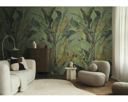 Woonkamer met vliesfotobehang met grote bananenbladeren, een getextureerde bank, een ronde fauteuil, een houten dressoir en een licht tapijt.