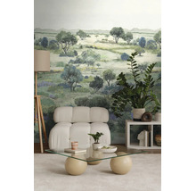 Modern interieur met landschapsbehang, een witte gestoffeerde fauteuil, een glazen tafel en een vloerlamp op een driepoot.