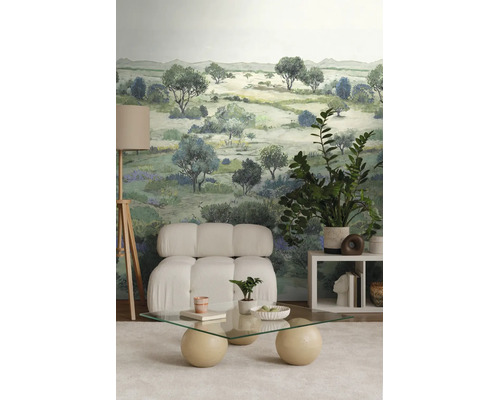 Modern interieur met landschapsbehang, een witte gestoffeerde fauteuil, een glazen tafel en een vloerlamp op een driepoot.