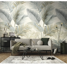 Woonkamer met behang met grote palmbladeren in zachte tinten, grijze bank, zwarte salontafel en vloerkleed op parketvloer.
