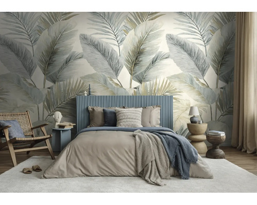 Moderne slaapkamer met groot fotobehang met palmbladeren, een gestoffeerd bed en een houten fauteuil.