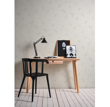 Vliesbehang met abstract patroon achter een minimalistisch houten bureau, een zwarte stoel en een bureaulamp.