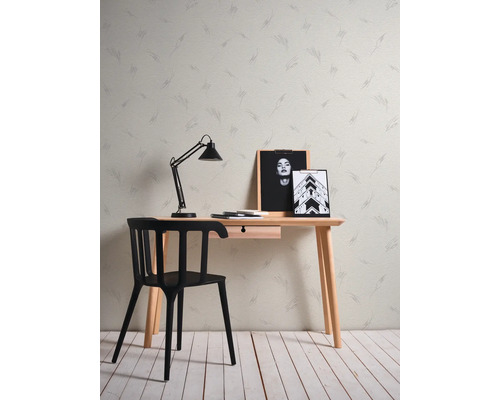 Vliesbehang met abstract patroon achter een minimalistisch houten bureau, een zwarte stoel en een bureaulamp.