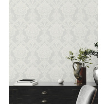 Vliesbehang met barok damastpatroon achter een donker bureau met decoratie.
