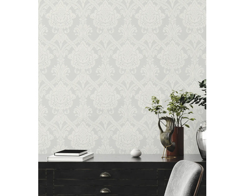 Vliesbehang met barok damastpatroon achter een donker bureau met decoratie.