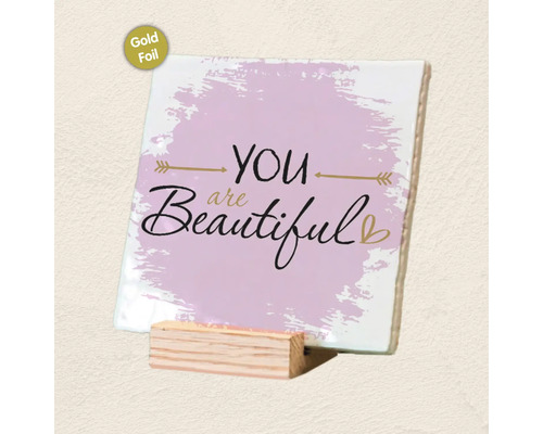 Decoratieve tegel met de tekst You are beautiful, goudfolie-afwerking en een bijbehorende houten standaard.