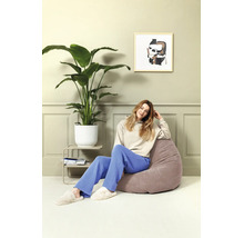 Lichte woonkamer met lambrisering, een grote kamerplant in een witte pot en een vrouw op een zitzak met textuur.
