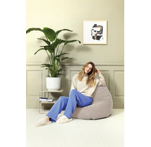 Vrouw zit op een comfortabele, ronde zitzak in een modern ingerichte woonkamer met kamerplant en wanddecoratie.