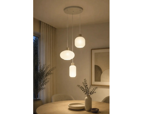 Drielichts hanglamp met wit geribbelde glazen kappen in diverse vormen boven een houten eettafel.