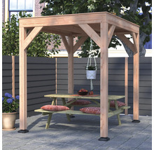 Een vrijstaande houten pergola met plat dak op een terras, met daaronder een houten picknicktafel met zitkussens en een hangplant.