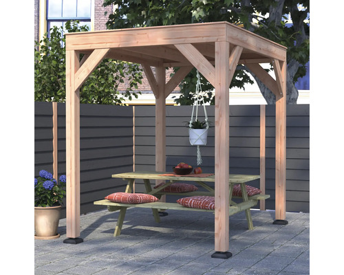 Een vrijstaande houten pergola met plat dak op een terras, met daaronder een houten picknicktafel met zitkussens en een hangplant.