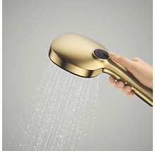 Een hand houdt een goudkleurige handdouche in werking vast waar water uit stroomt, met een drukknop aan de bovenkant.