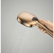 Handdouche in goudlook met stromend water, vastgehouden door een hand.