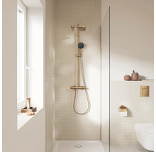 Moderne badkamer met goudkleurig douchesysteem, regendouche, handdouche en lichte tegels.