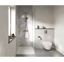 Moderne badkamer met inloopdouche, regendouche, douchebak, hangend toilet, bedieningspaneel en vloer met betonlook.