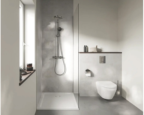 Moderne badkamer met inloopdouche, regendouche, douchebak, hangend toilet, bedieningspaneel en vloer met betonlook.
