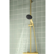 Goudkleurig douchesysteem met stromende handdouche op een betegelde wand.