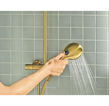 Hand houdt een handdouche met straalregelaar vast waar water uit stroomt, voor een betegelde wand.